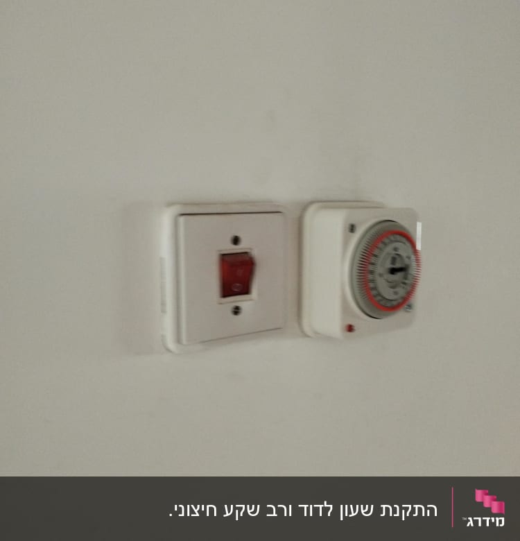 שקע חשמלי עם מתג אדום וטיימר על קיר לבן